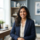 A happy South Asian woman smiling in a bright, modern office space.